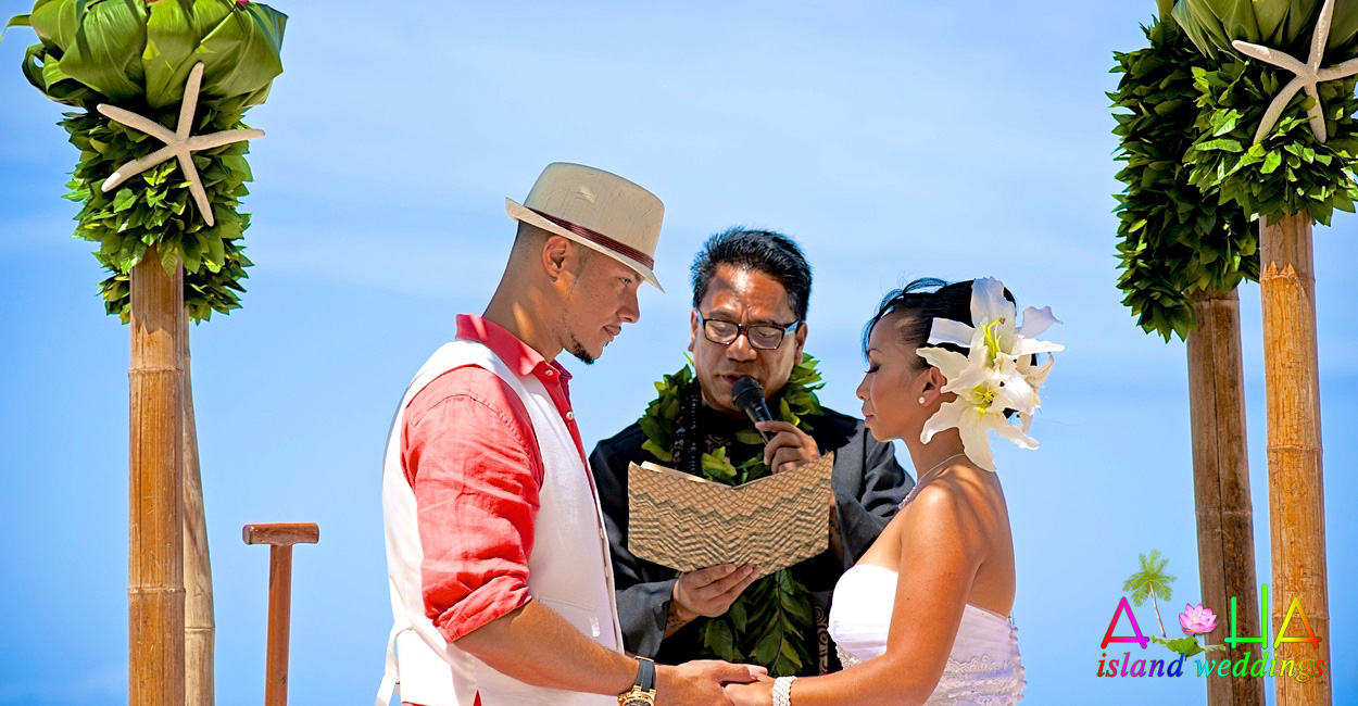 Minister reading the vows to the couple under a beach arch decorated with starfish